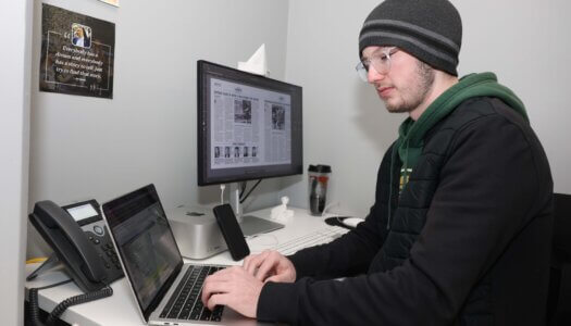 A student works on the newspaper on his laptop.