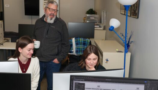 A professor overlooks students working on computers.