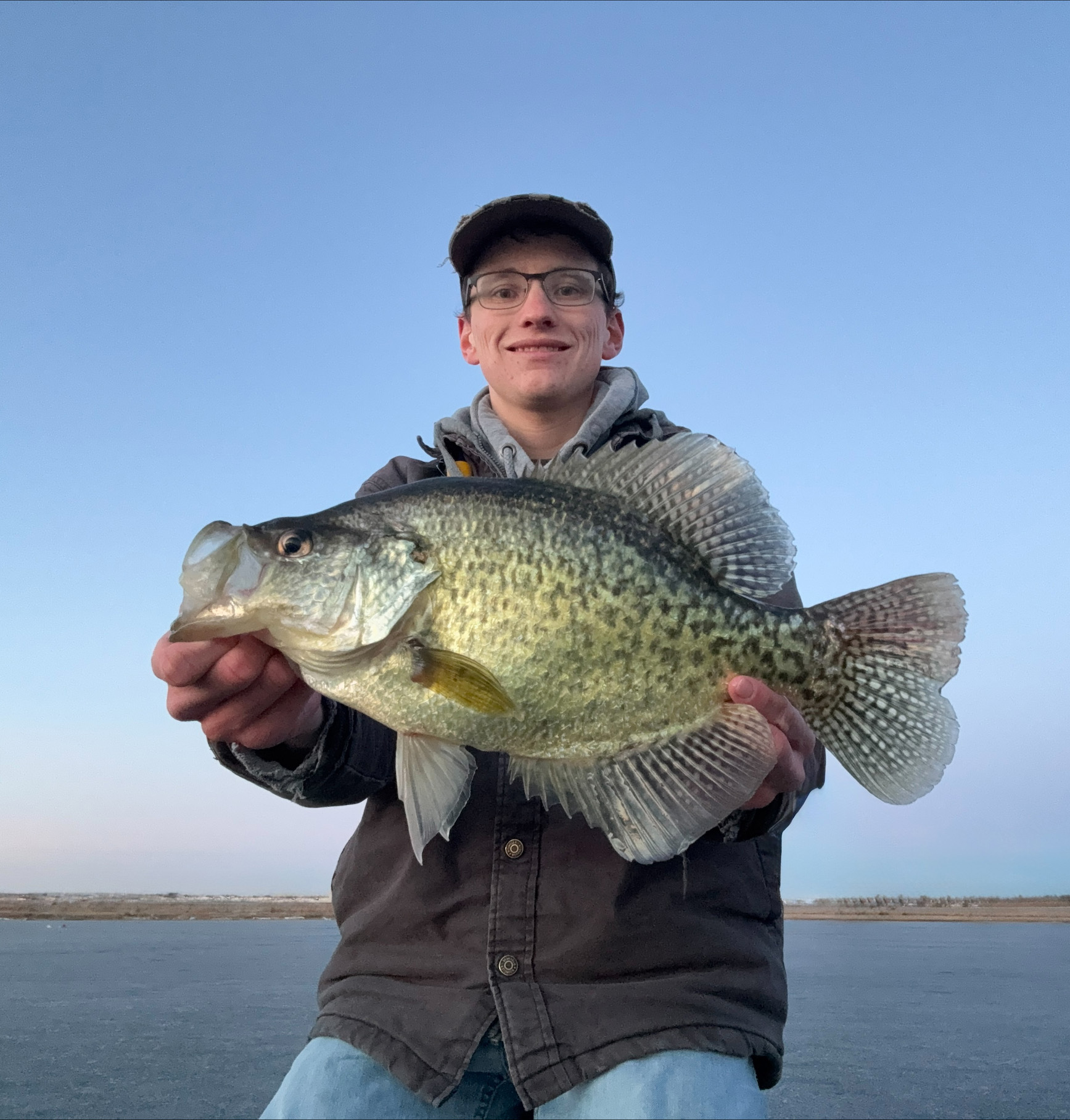Connor Banzhaf holds up a crappie while ice fishing.