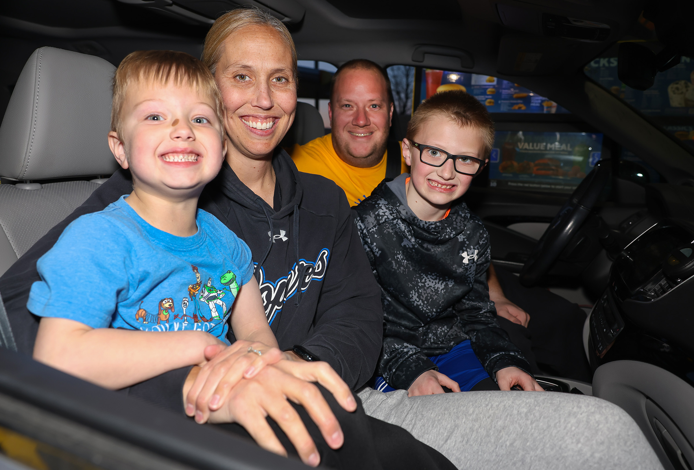 Drew and Nicole Johnson pose for a photo in their vehicles with their two sons at Sonic.