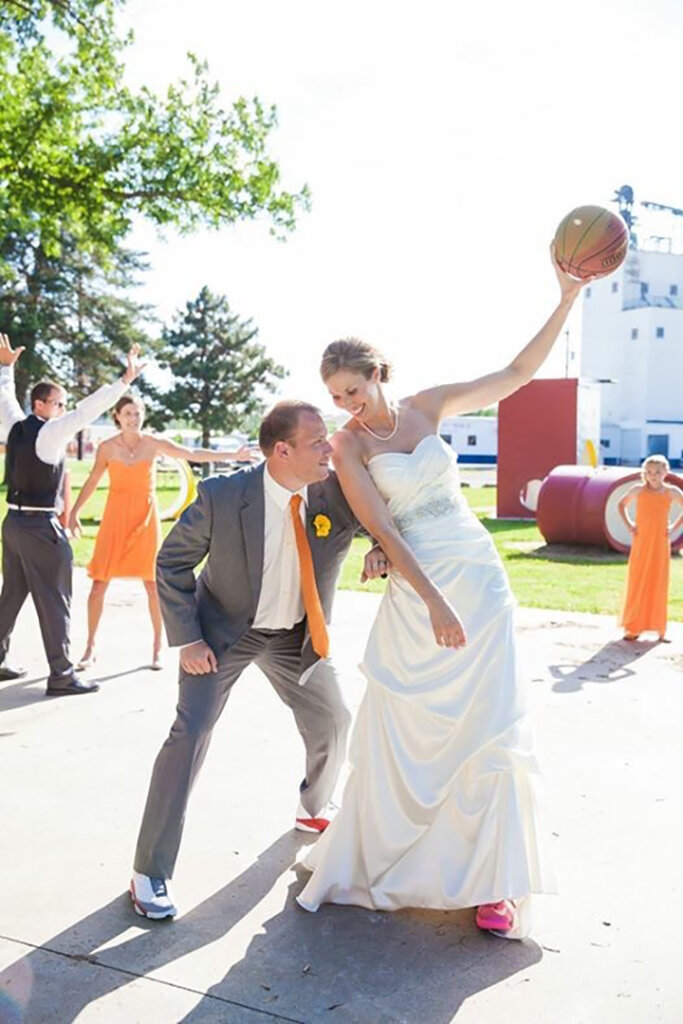 Drew and Nicole Johnson play one-on-one basketball in their wedding attire.