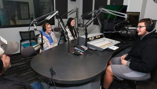 Students gather around a desk at the student radio station.