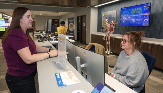 A woman talks to another employee at the Loper Success Hub desk.