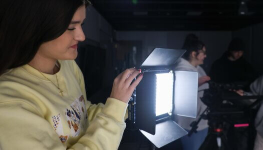A student operates a studio light.