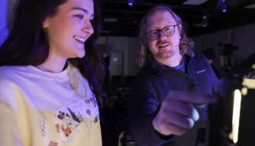 A professor shows a student how to operate a studio light.