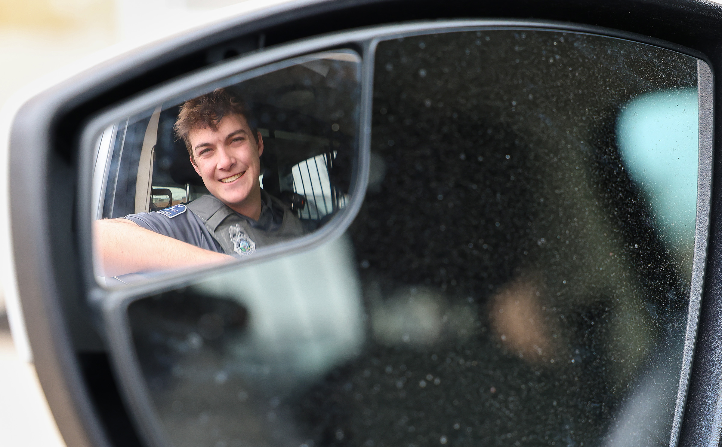 Zach Arner is pictured inside his Kearney Police Department vehicle, with his face reflecting in the mirror.