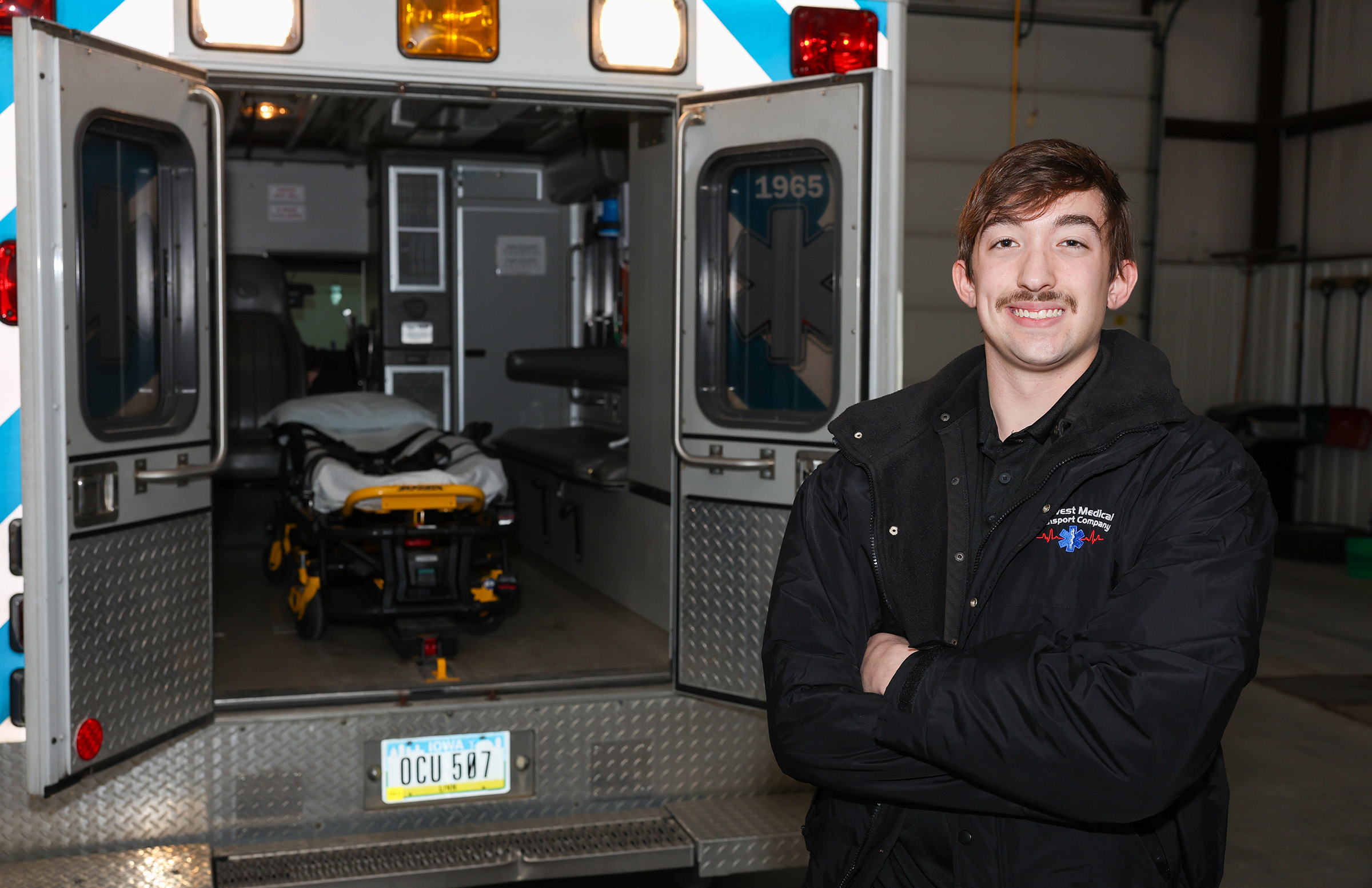 Carter Moss poses for a photo with a Midwest Medical Transport ambulance in the background.