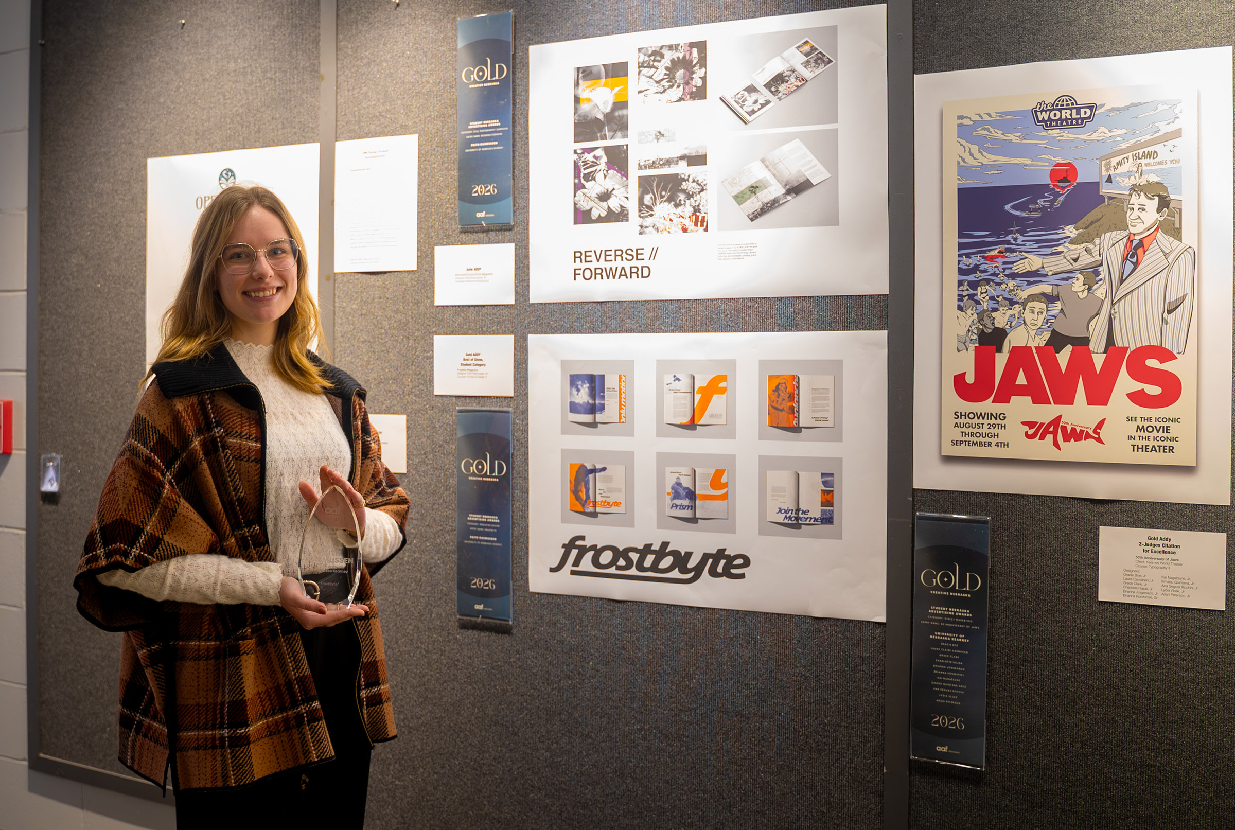 UNK senior Faith Rasmussen poses for a photo with her design projects and awards.