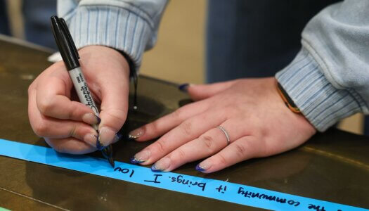 A UNK student writes a message a support during "I Love NU" Day.