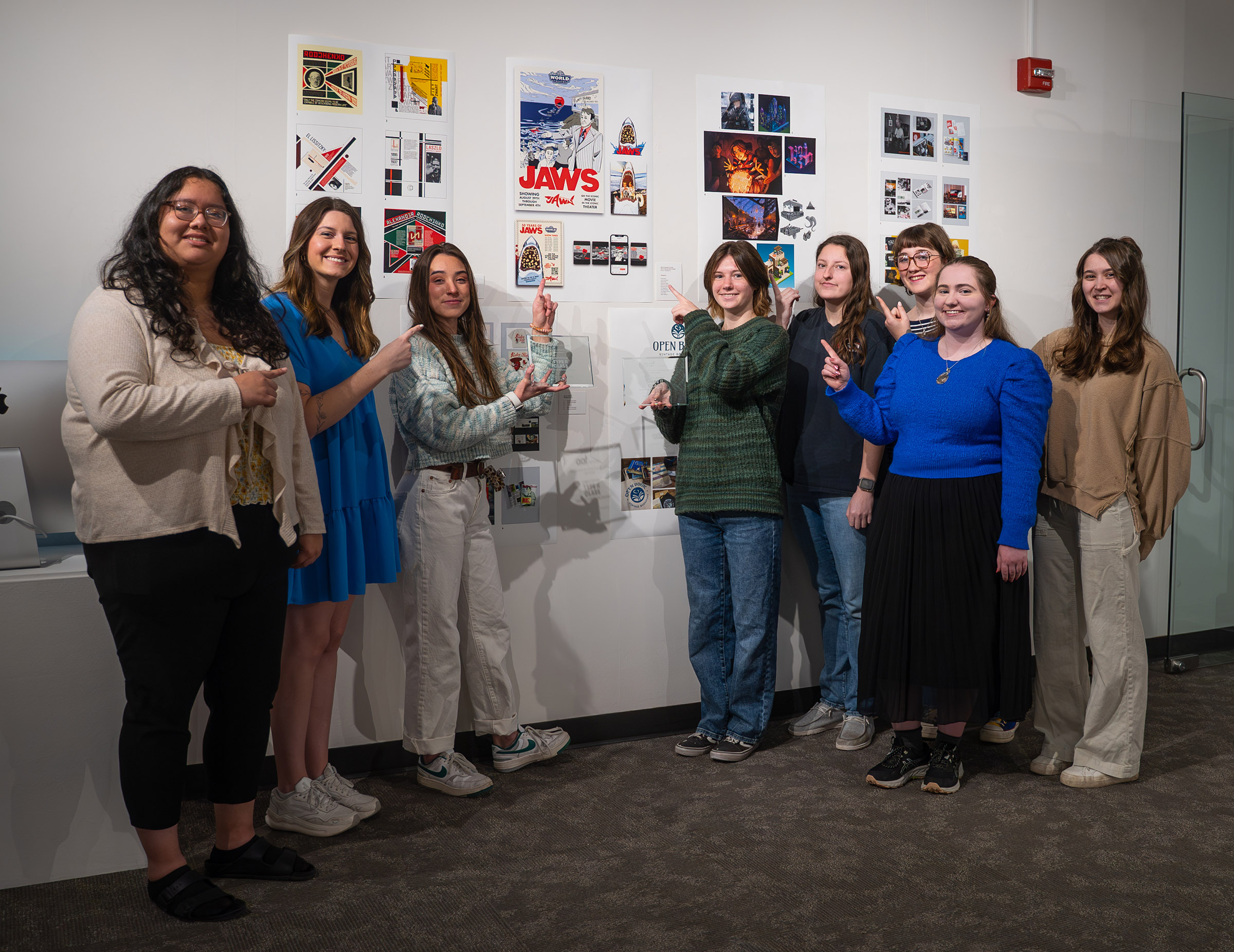 UNK students from the Typography II class pose for a photo with their design for the "Jaws" 50th anniversary.