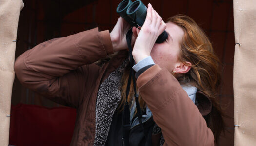 Katie Arens uses binoculars to watch sandhill cranes along the Platte River.