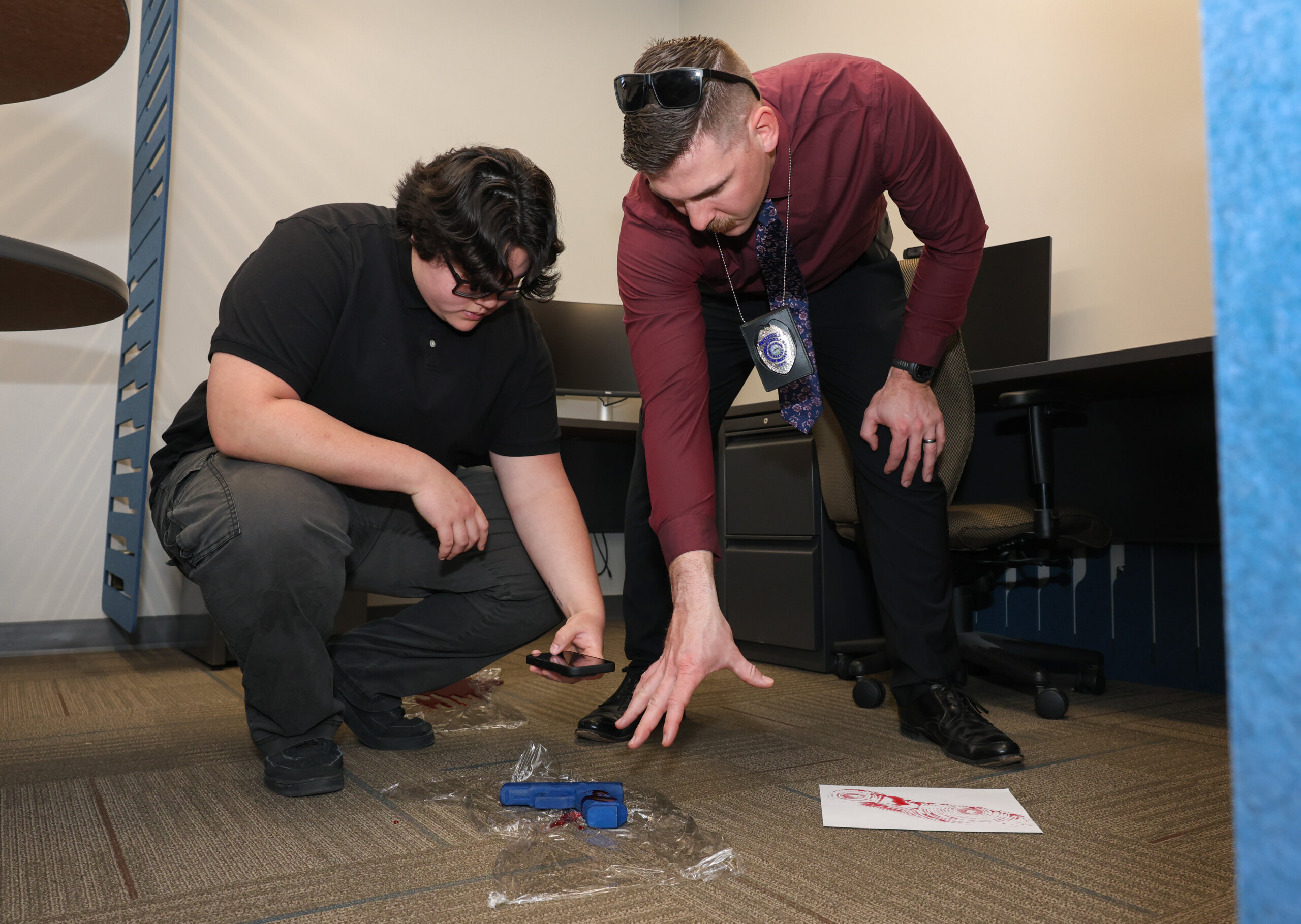 A student takes photos in a staged crime scene while a Nebraska State Patrol employee teaches.