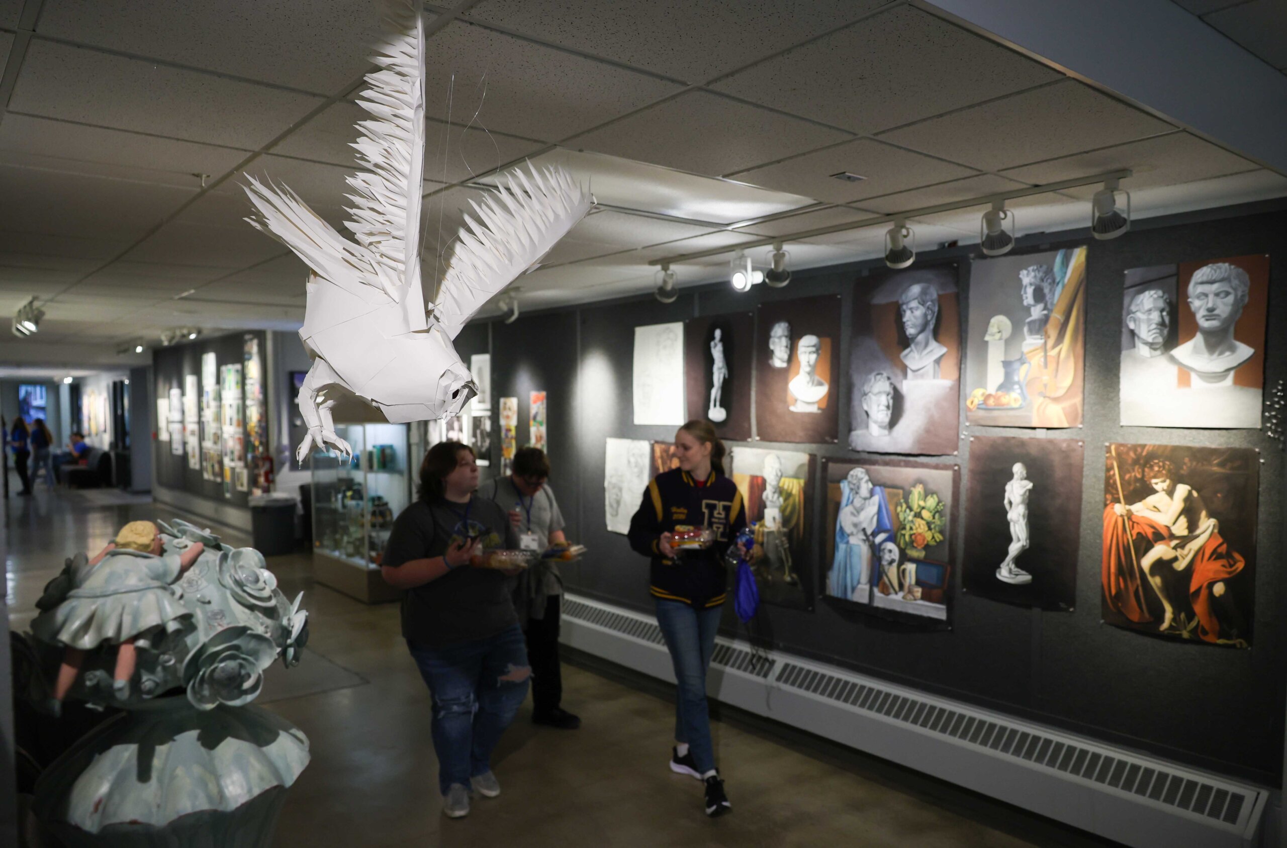 Students walk down a hallway filled with art.