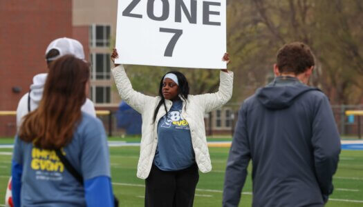 A zone leader holds up a sign for students.