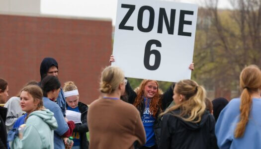 A zone leader holds up a sign for students.