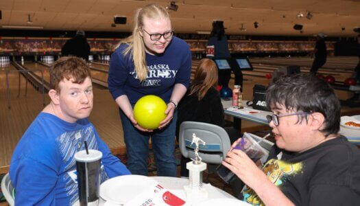 A UNK student assists during Buddy Bowling at Big Apple Fun Center.