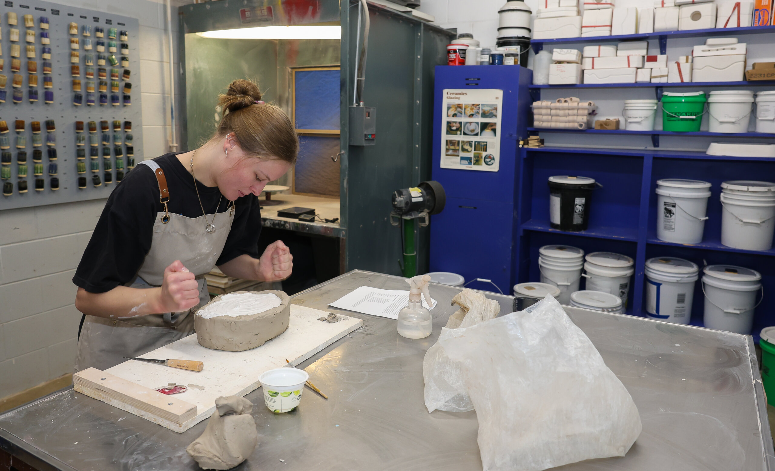 A student forms a ceramic piece.