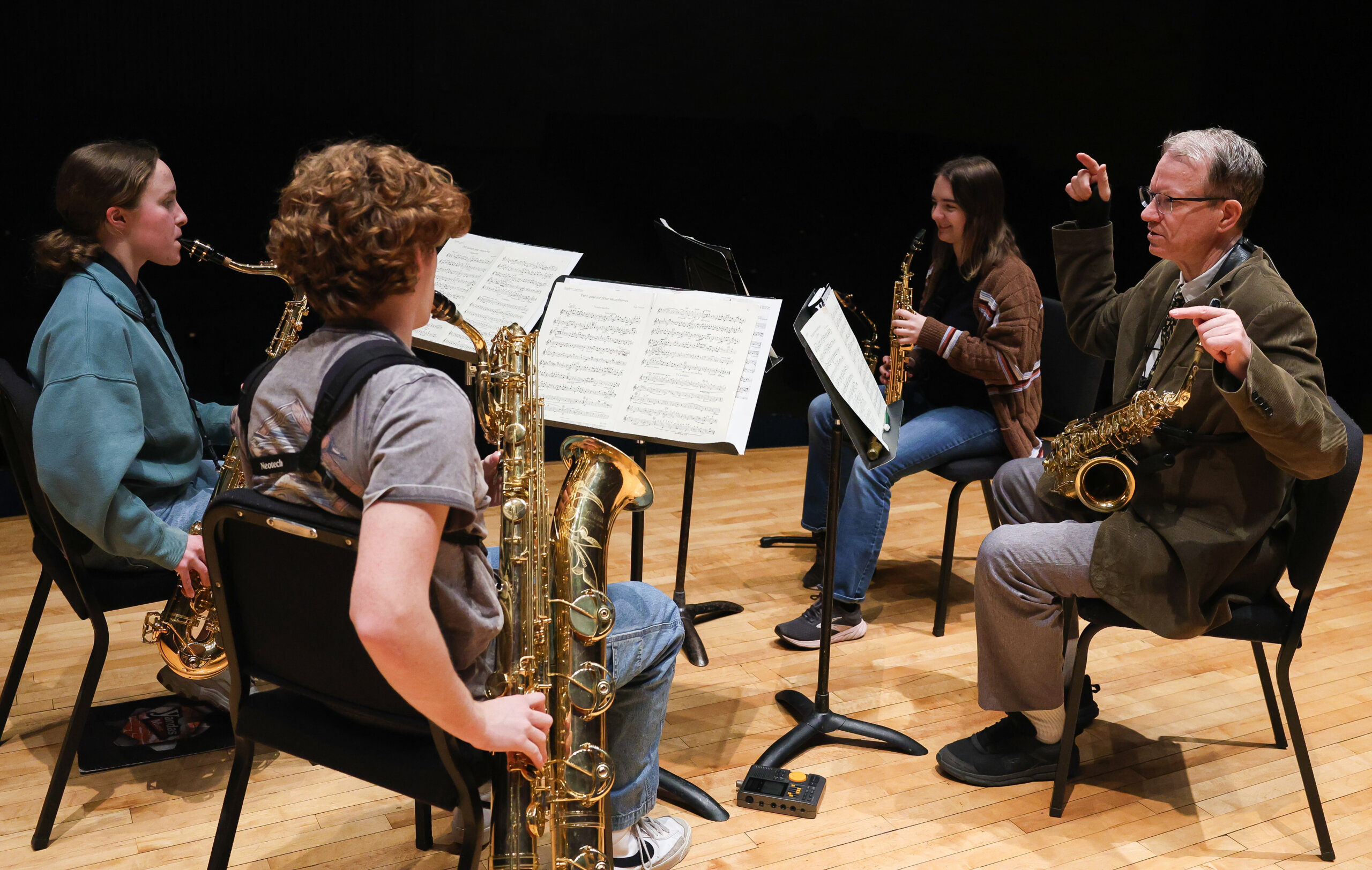 Four people play the saxophone.