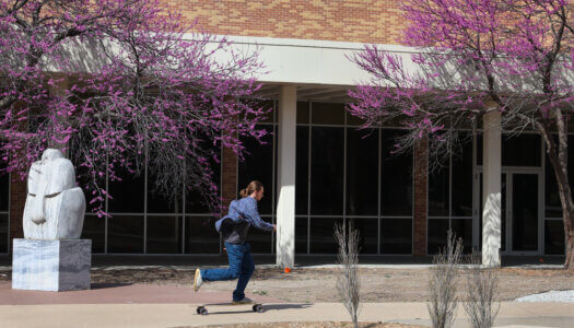 A student skateboards in front of the Fine Arts Building (Photo by Erika Pritchard, UNK Communications).