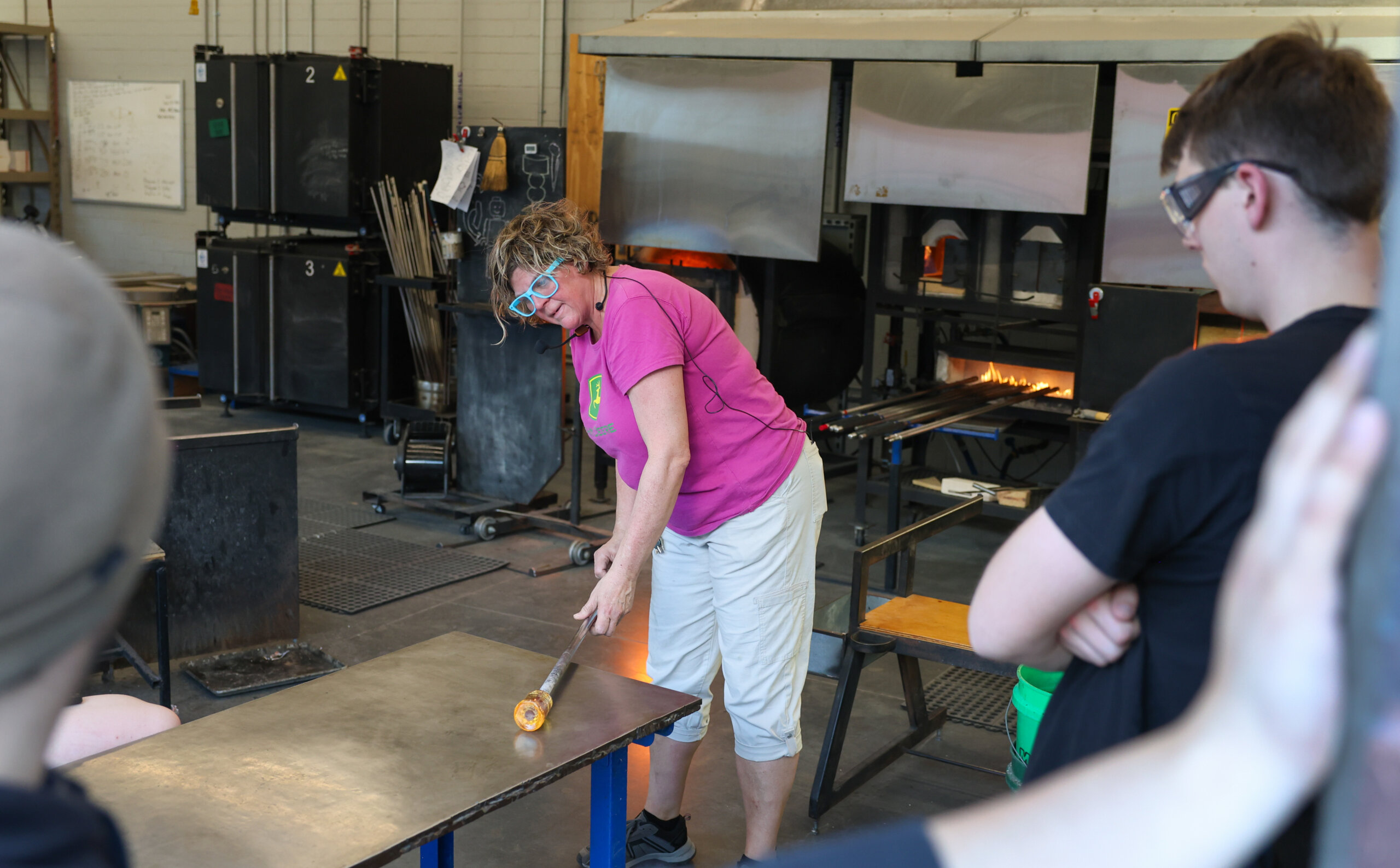 A woman rolls hot glass on a table.