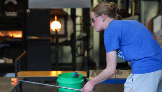 A student shapes glass in the glassblowing studio (Photo by Erika Pritchard, UNK Communications).