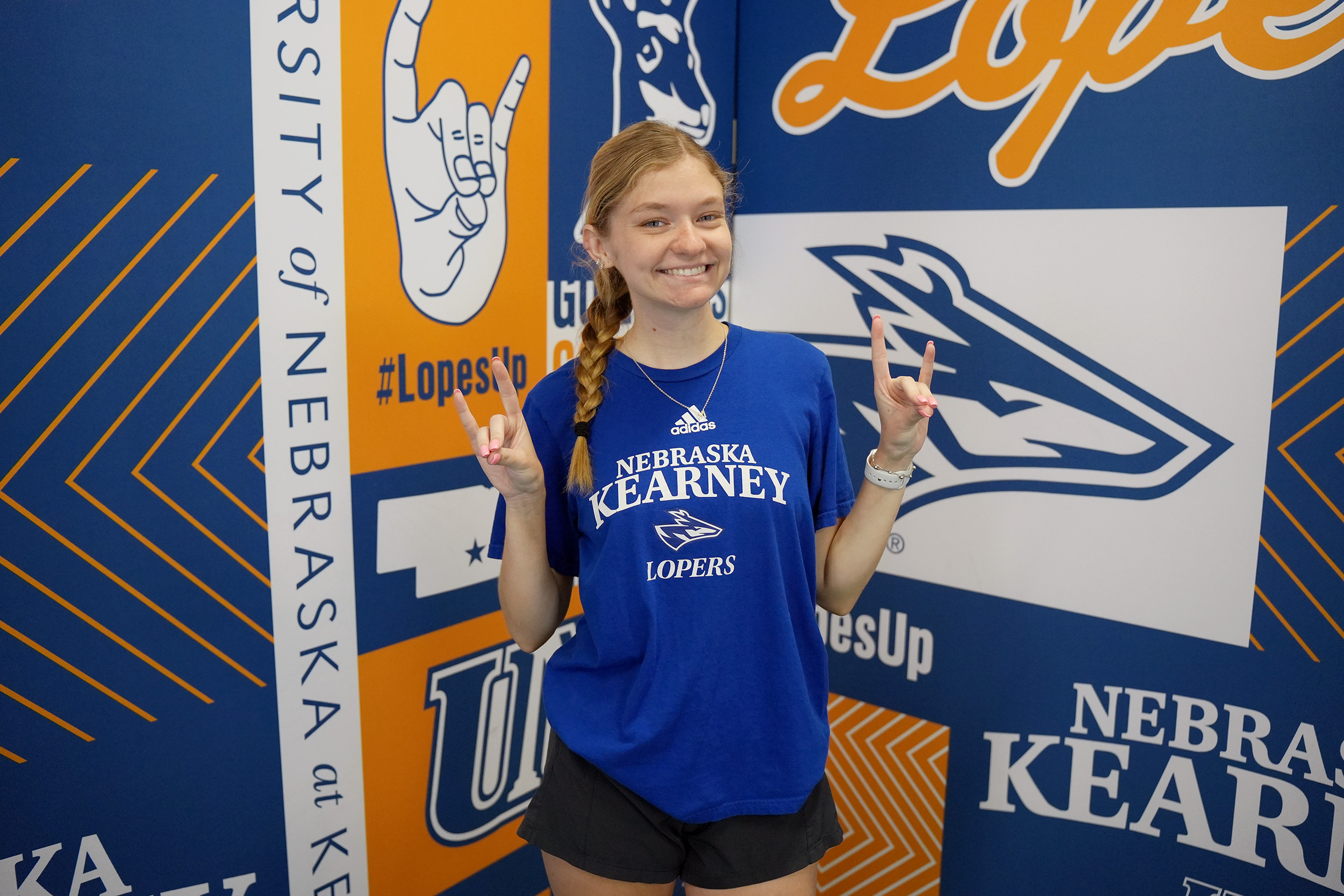 Kayla Rover poses for a photo in front of a UNK Athletics backdrop.
