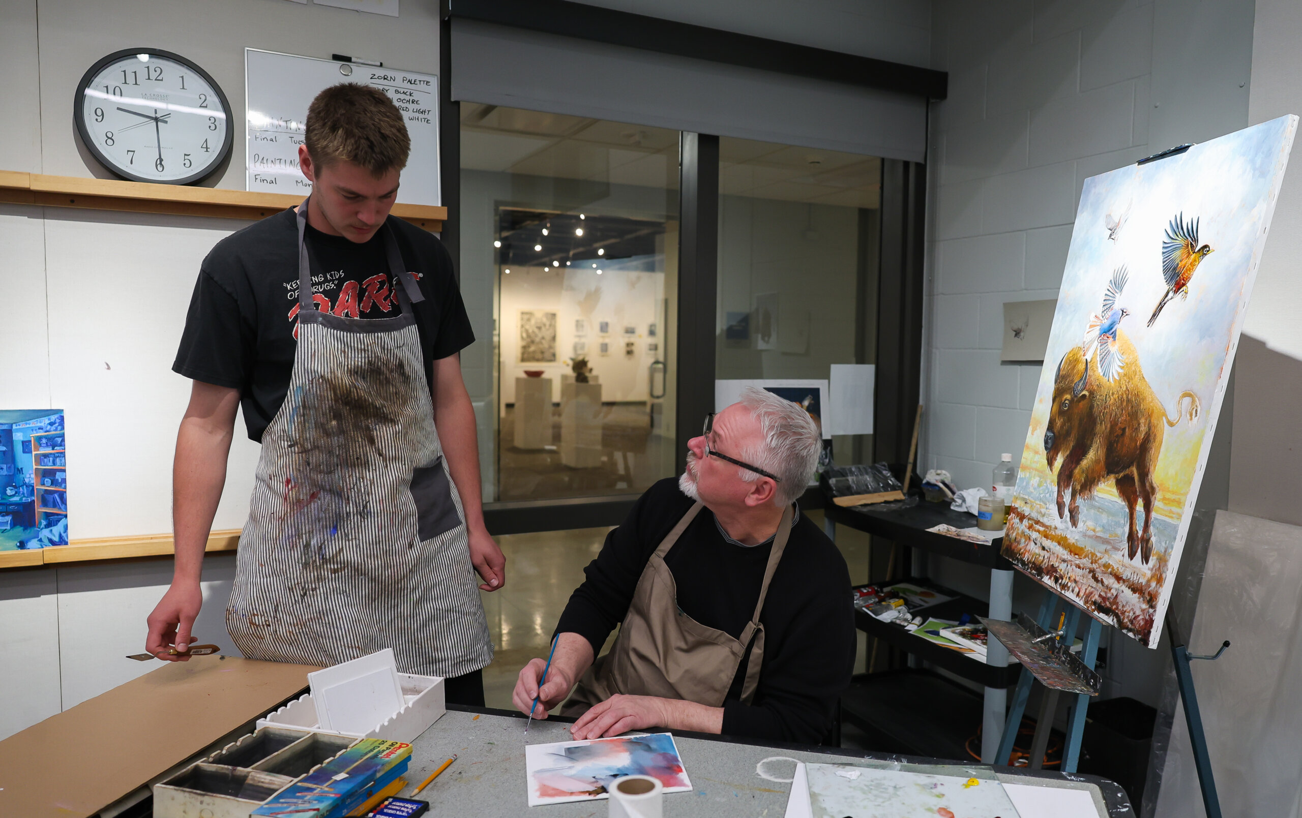 A man teaches a student about painting.