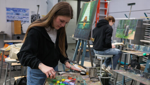A student scrapes paint from a palette in painting class (Photo by Erika Pritchard, UNK Communications).
