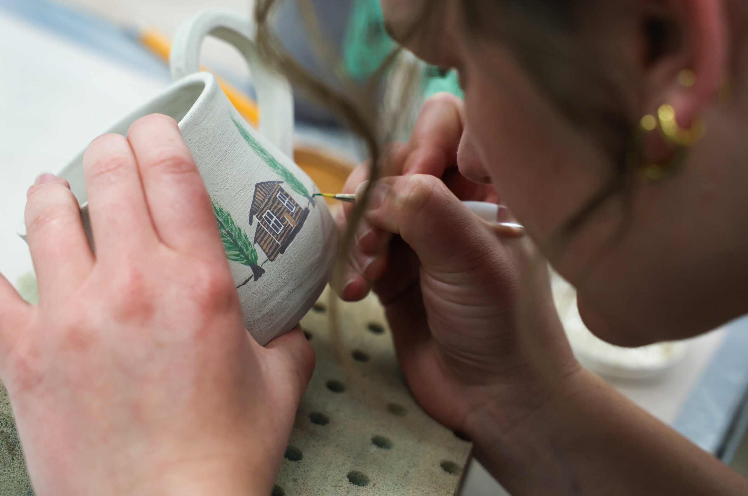 A student paints a mug.
