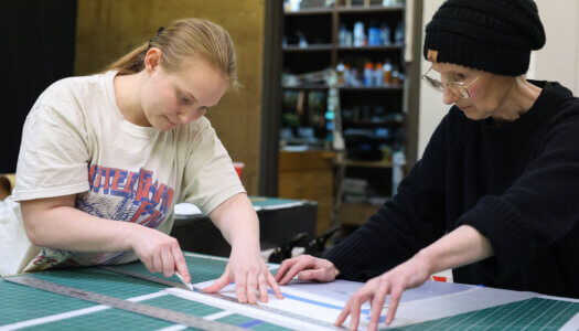 Victoria Goro-Rapoport, printmaking and drawing professor, assists a student in printmaking class (Erika Pritchard, UNK Communications).