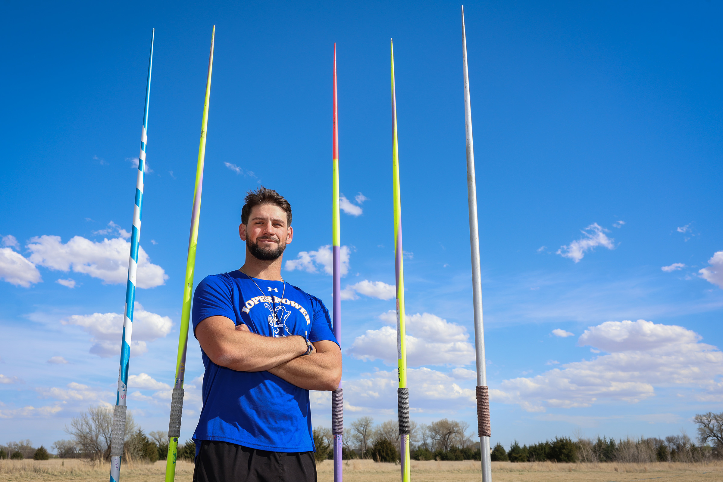 Rylan Basart poses for a photo with javelins in the background.