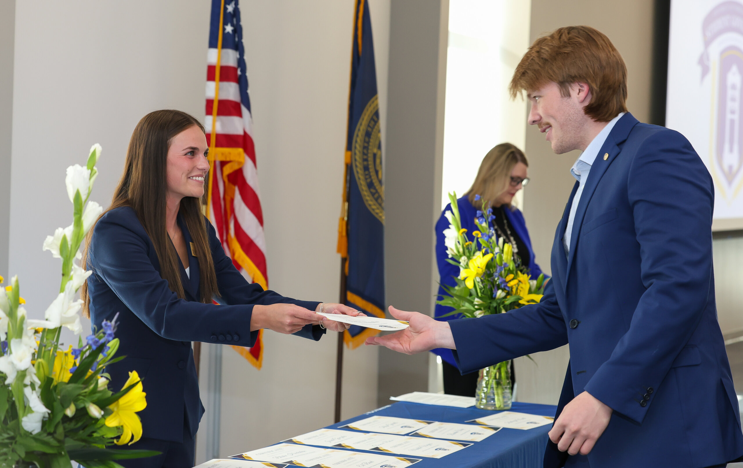 A female hands a man a certificate.