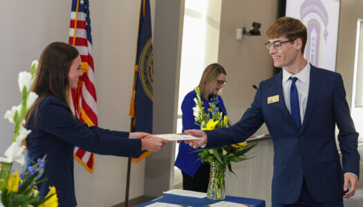 A previous student government member receives a certificate for his service.
