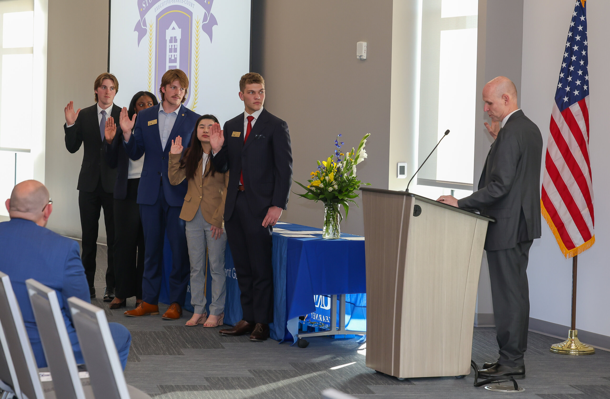 A group of students and a man raise their right hands.