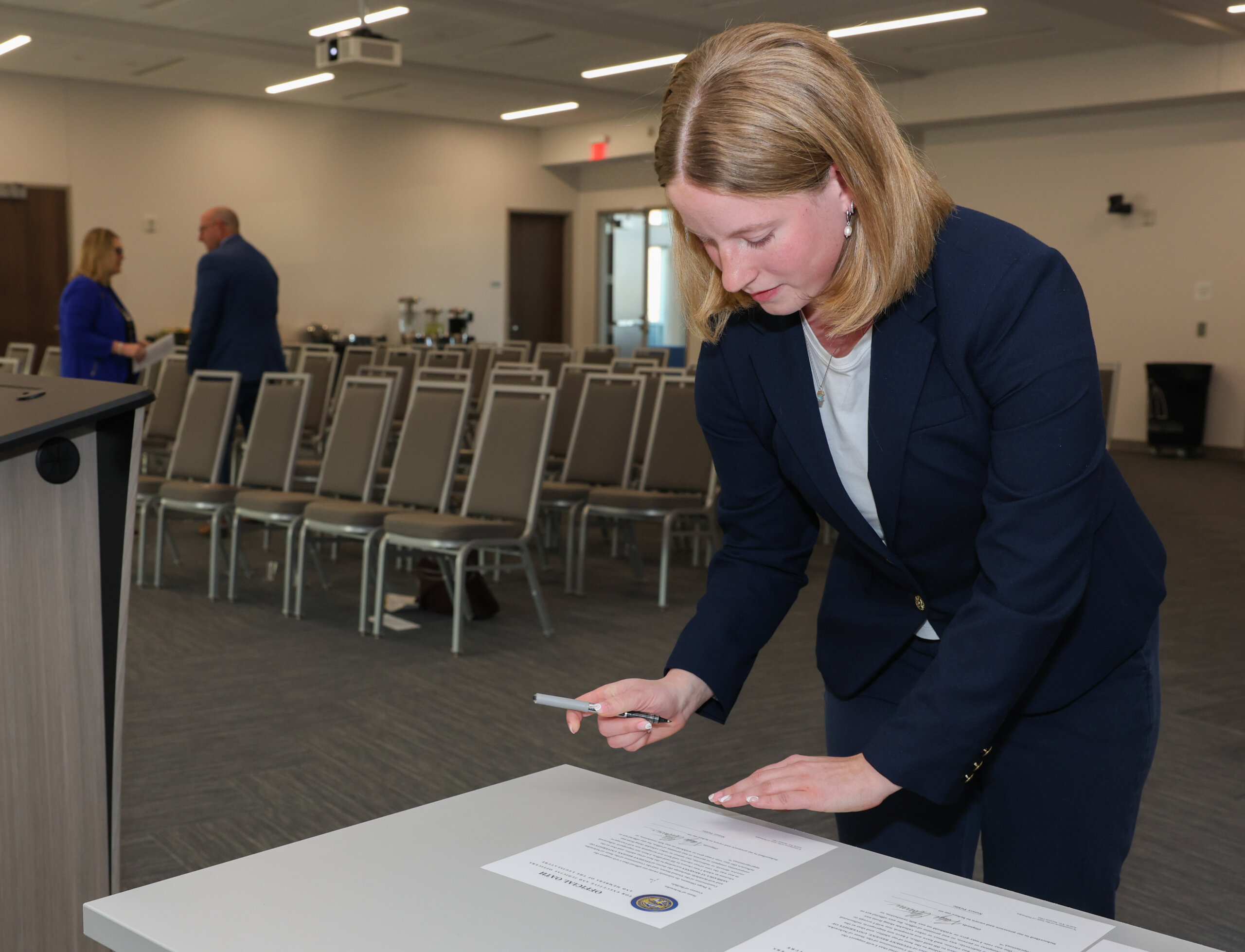 A female signs a document.