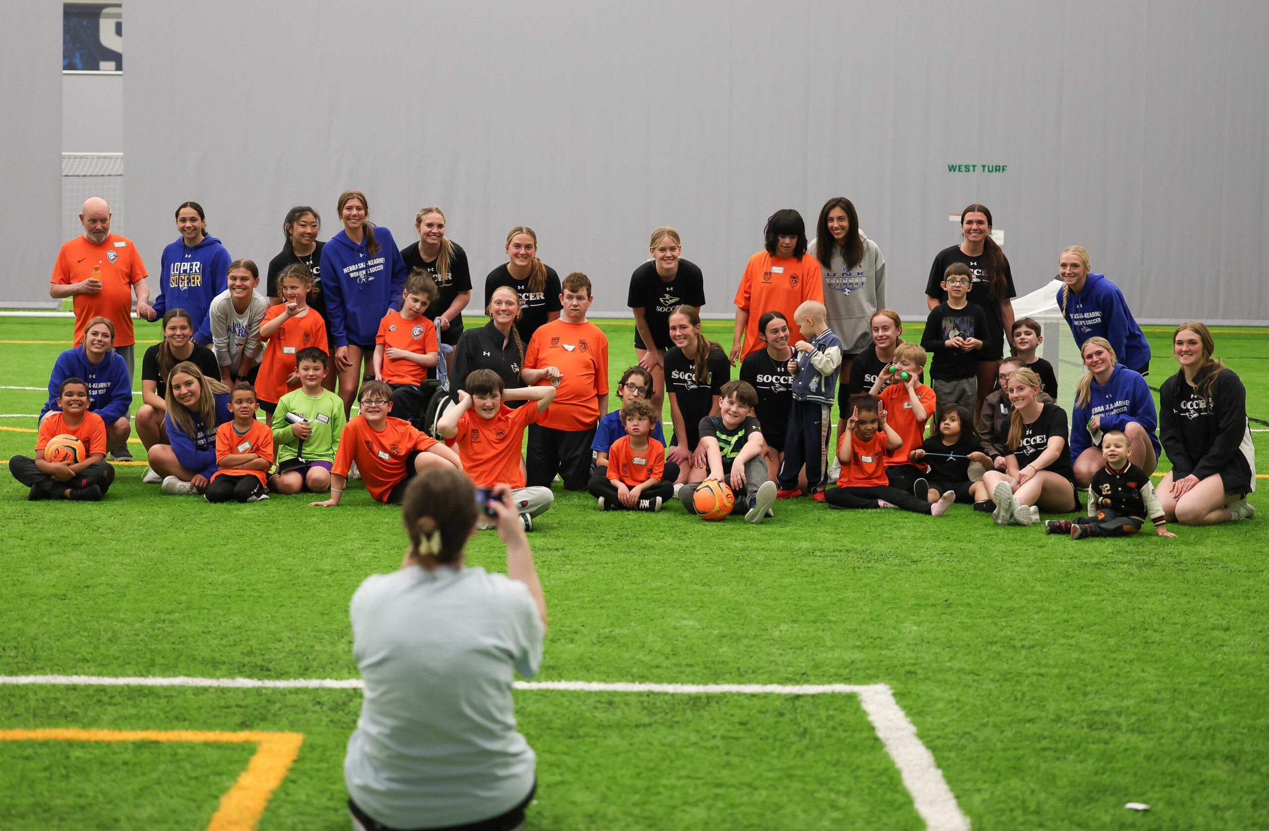 Members of the UNK women’s soccer team pose for a photo with TOPSoccer participants Monday evening at the Kearney SportsPlex.