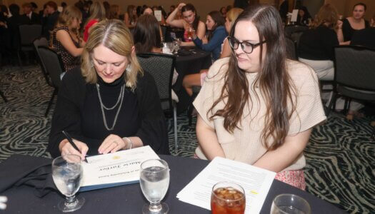 Renae Zimmer signs a scholarship award.