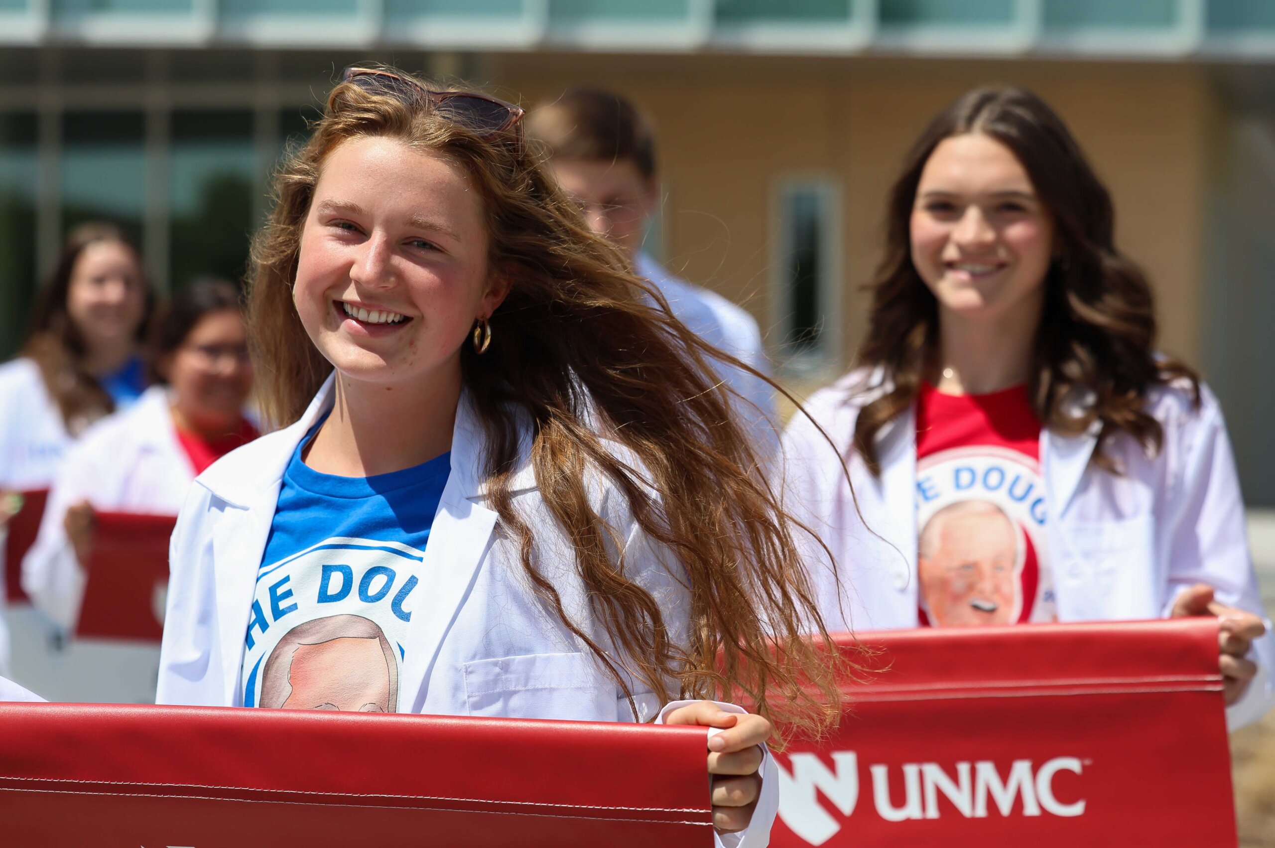 UNMC students carry banners representing the programs offered at the Douglas A. Kristensen Rural Health Education Complex.