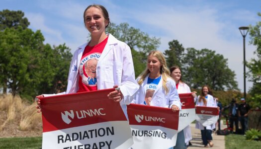 UNMC students carry banners representing the programs offered at the Douglas A. Kristensen Rural Health Education Complex.
