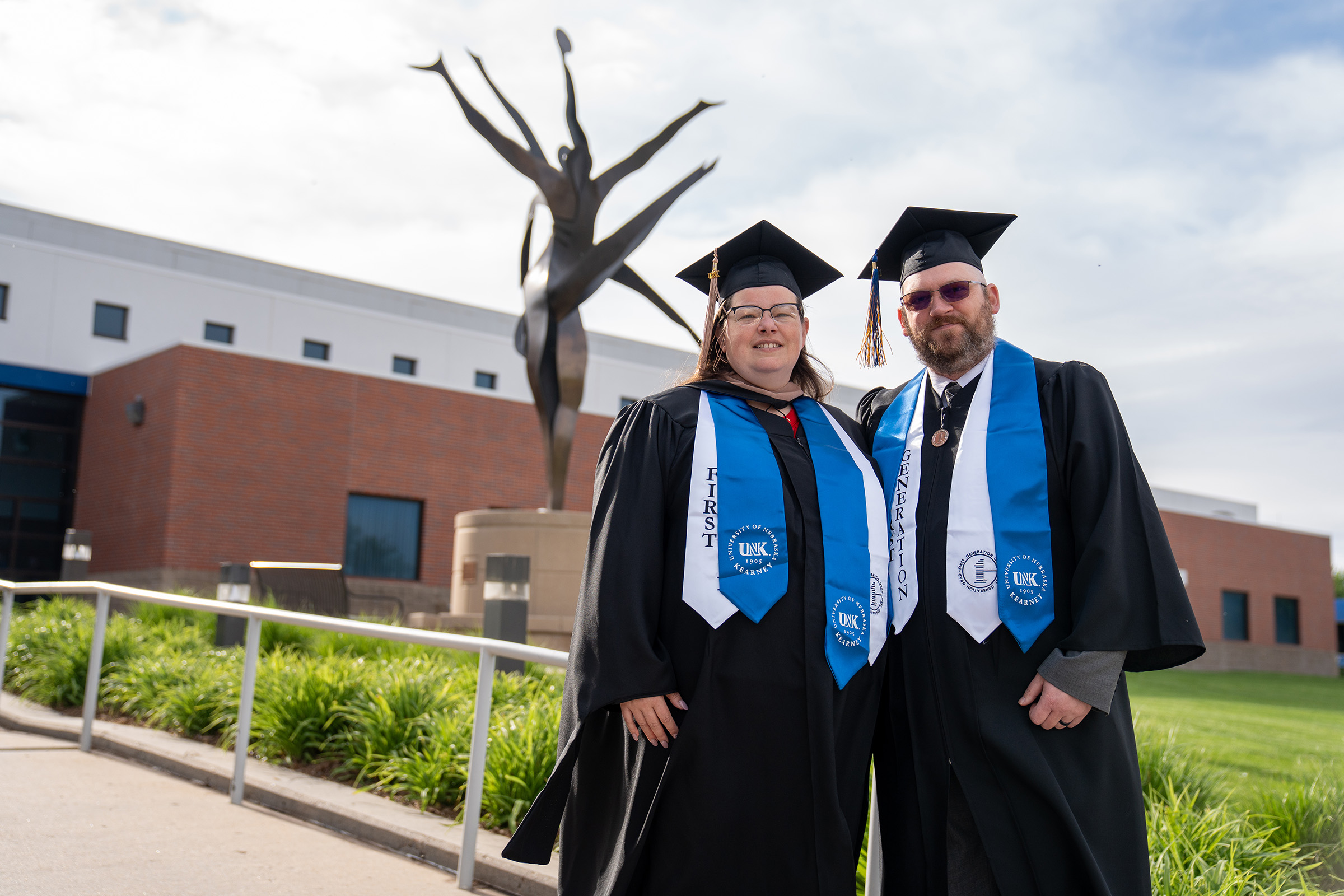 Dressed in their graduation regalia, Matthew and Kathy Welte are pictured outside UNK's Health and Sports Center on commencement day.