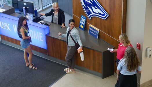A new student and her mother talk to staff at the UNK Welcome Desk.