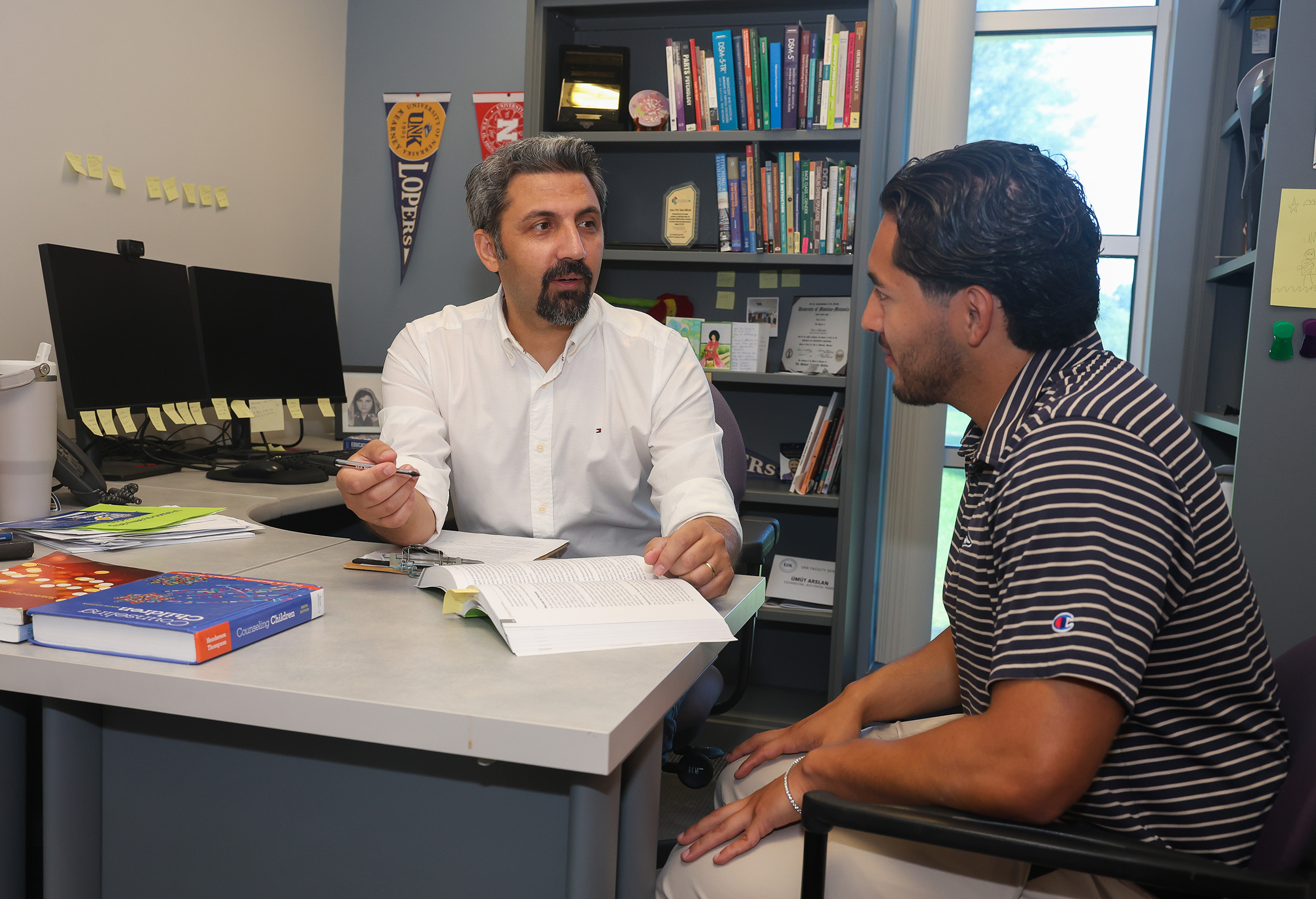Erick Leiva Lopez visits with UNK faculty member Ümüt Arslan in his office.