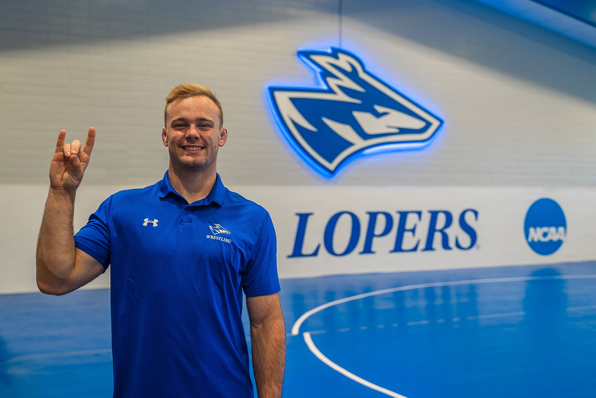 Gavyn Brauer poses for a photo in the UNK wrestling room.