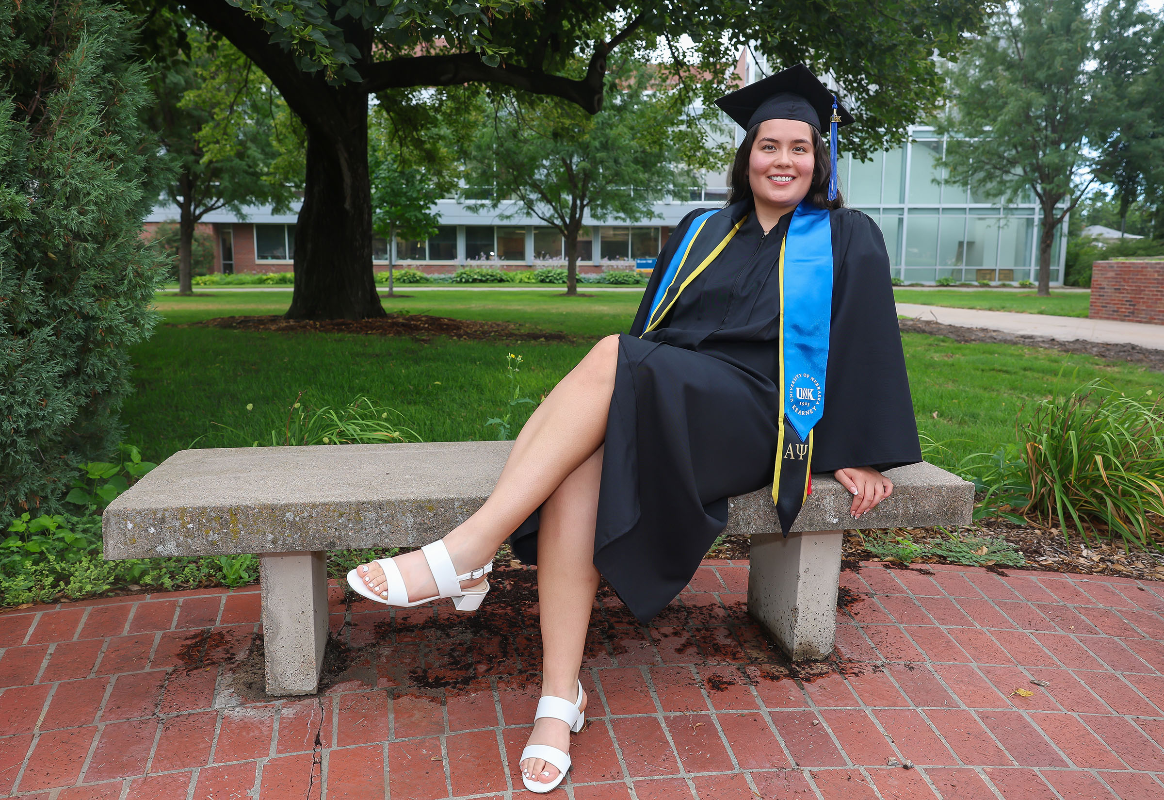 Laura Velasco poses for a photo on the UNK campus in her graduation cap and gown.