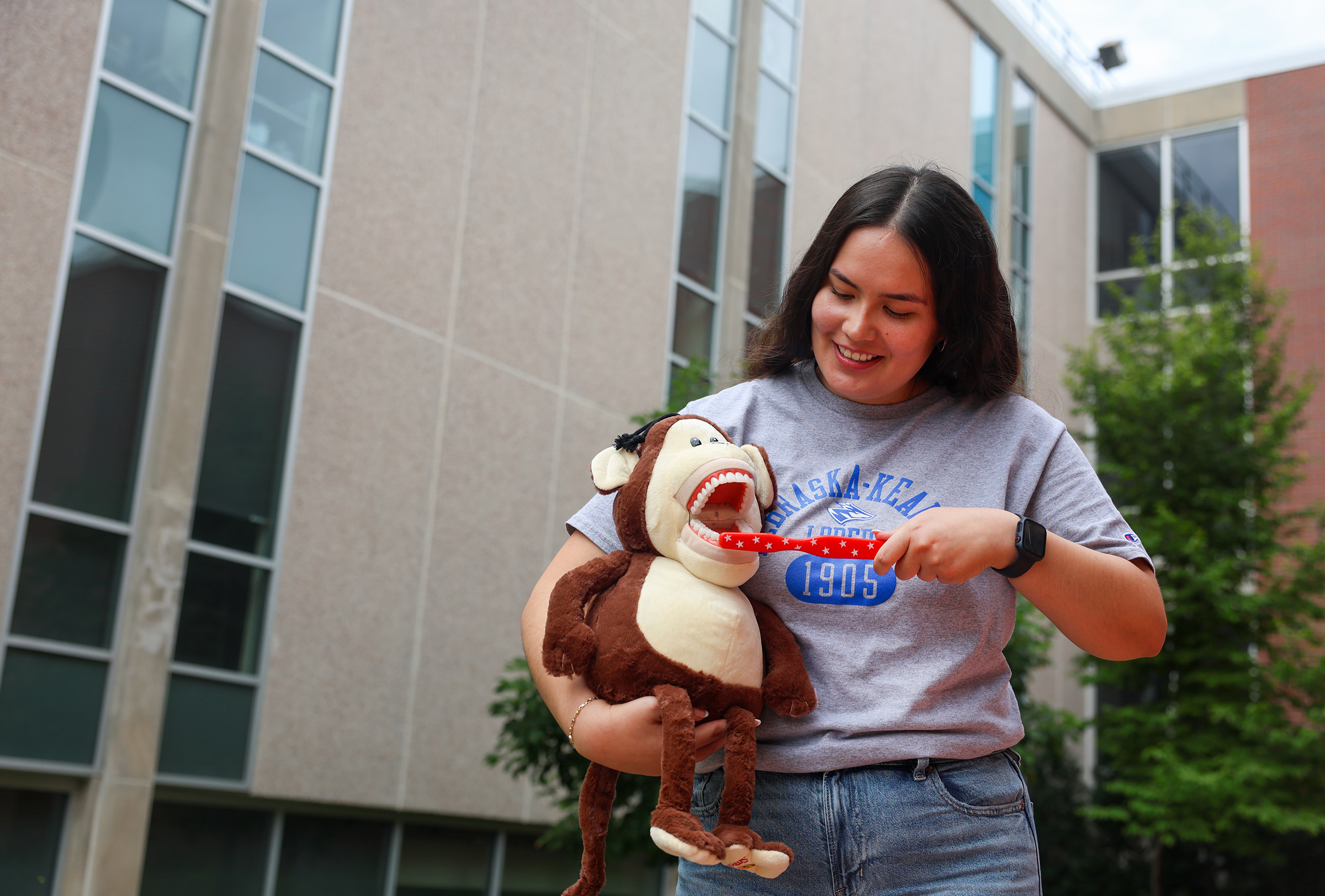 Laura Velasco poses for a photo with props used to teach kids about dental care.