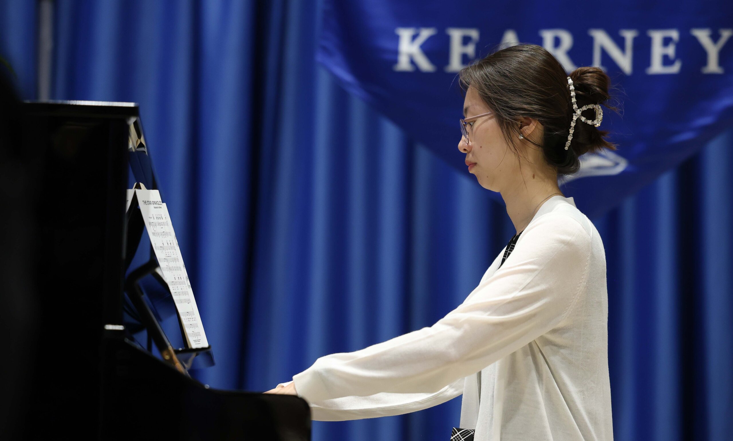 A woman plays piano during the national anthem.