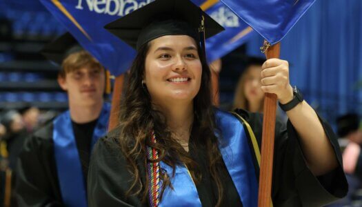 Laura Velasco carries the he College of Arts and Sciences flag.