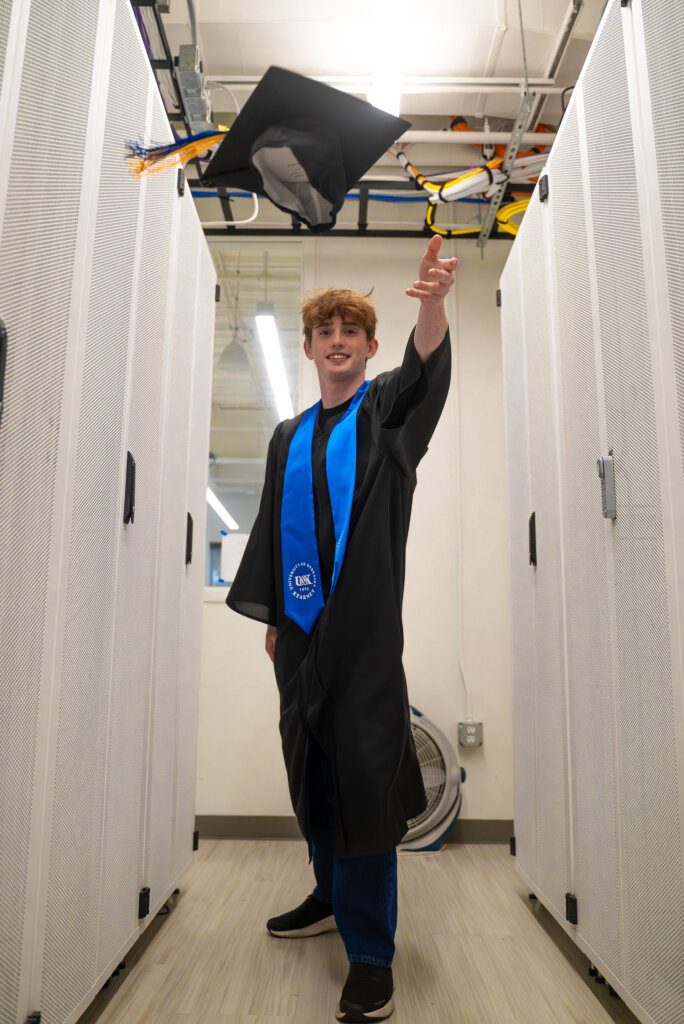 Thomas Safago tosses his graduation cap in the air.