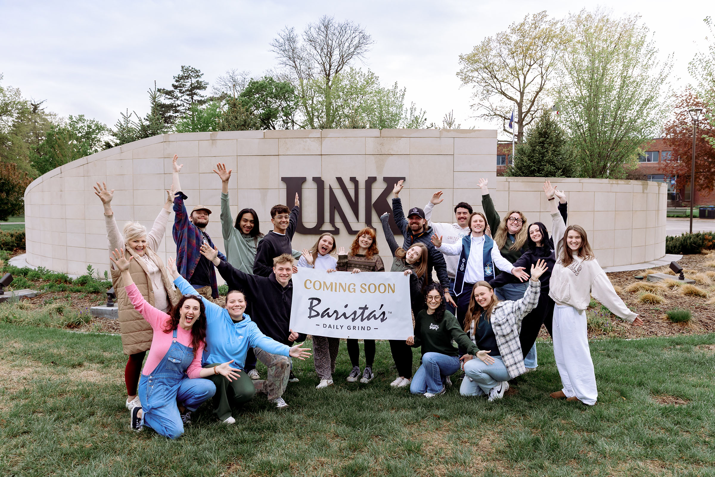 Barista's employees pose for a photo in front of a UNK sign.