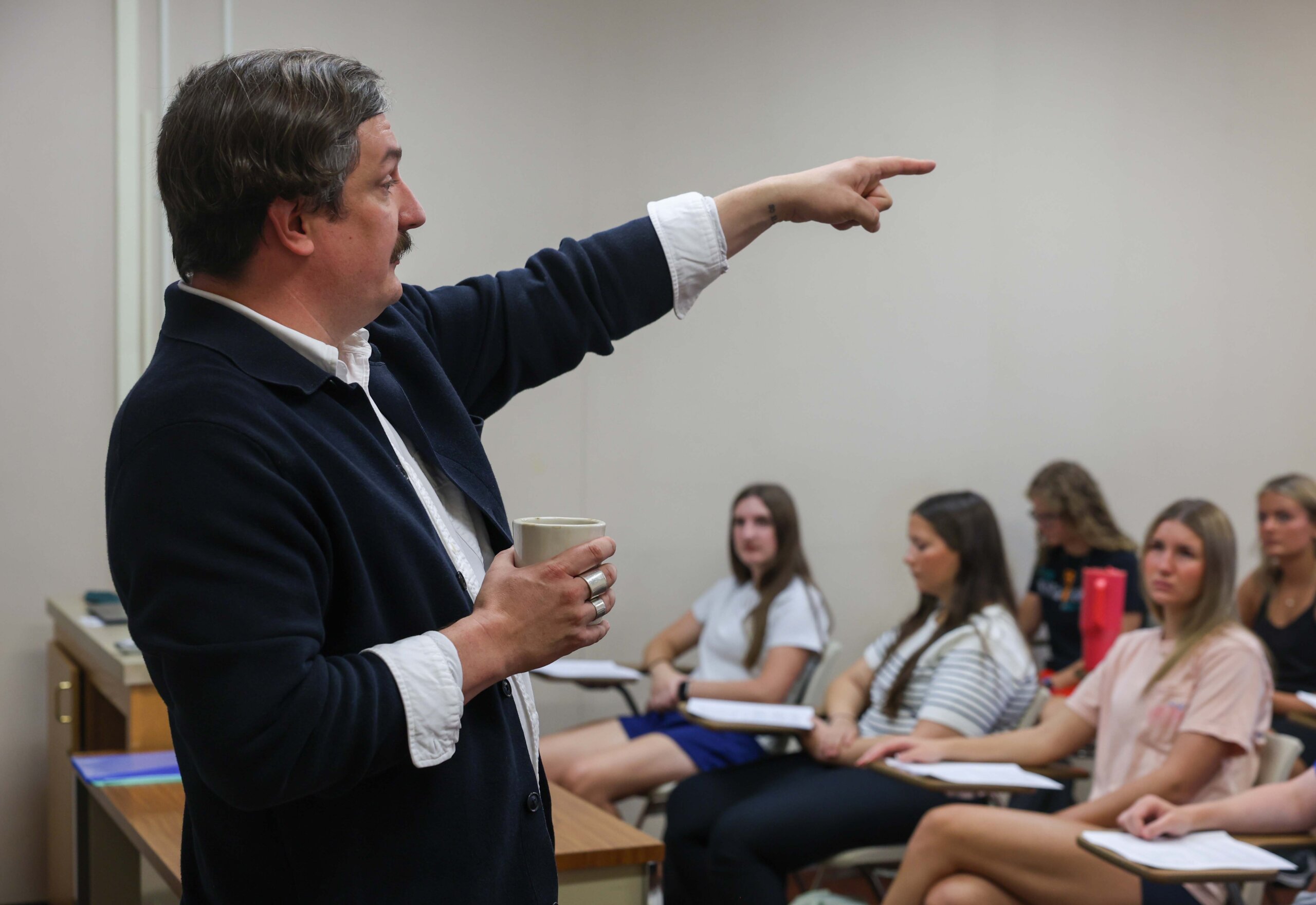 A professor points over a classroom of students.